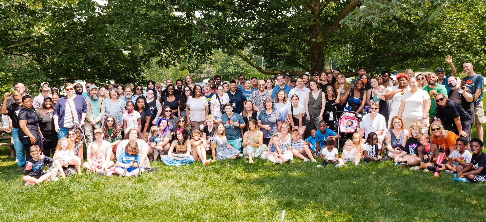 Photo of large group of people standing on grass in a park